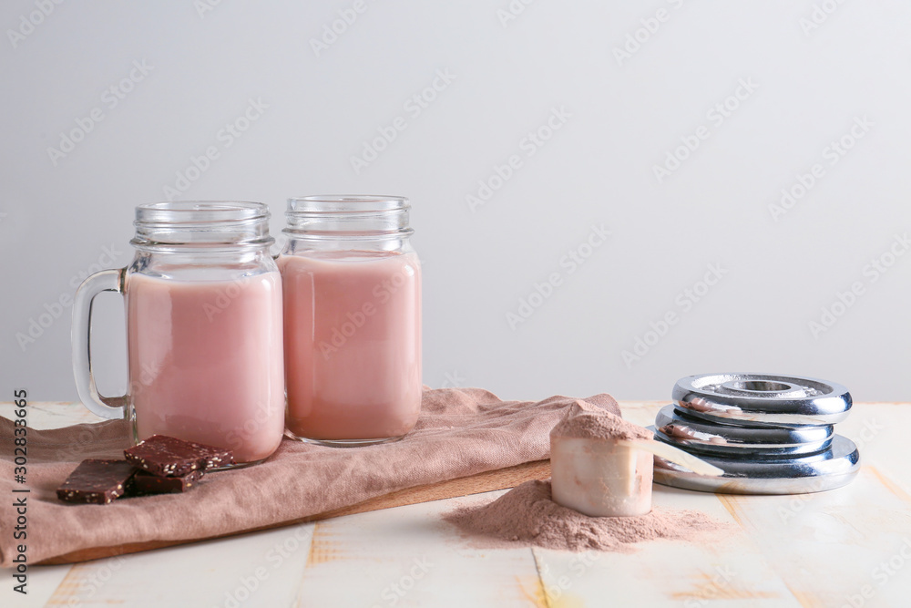 Mason jars of chocolate protein shake on light background