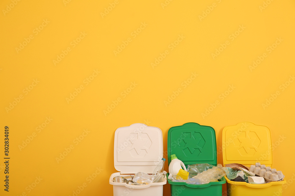 Containers with different types of garbage near color wall. Recycling concept