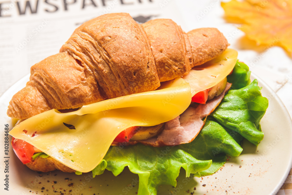 Tasty croissant sandwich on plate, closeup