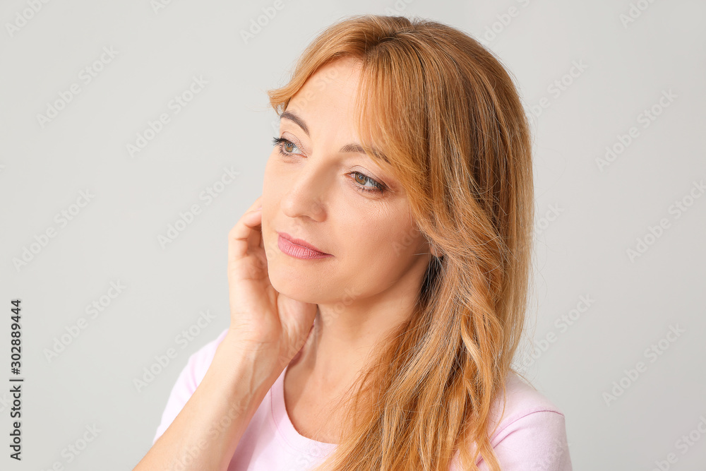 Mature woman with healthy skin on light background