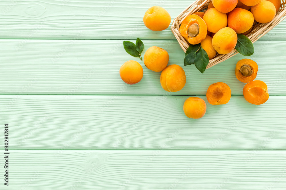 Collect apricots, green wooden background top view copy space, pattern with leaves