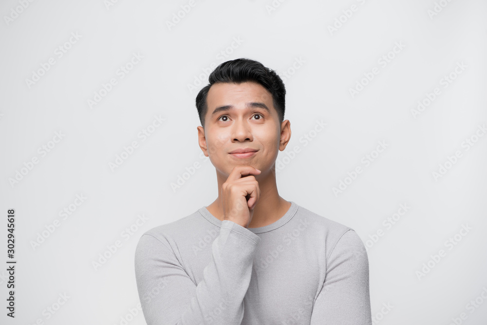 Thinking young Asian man isolated on white background.