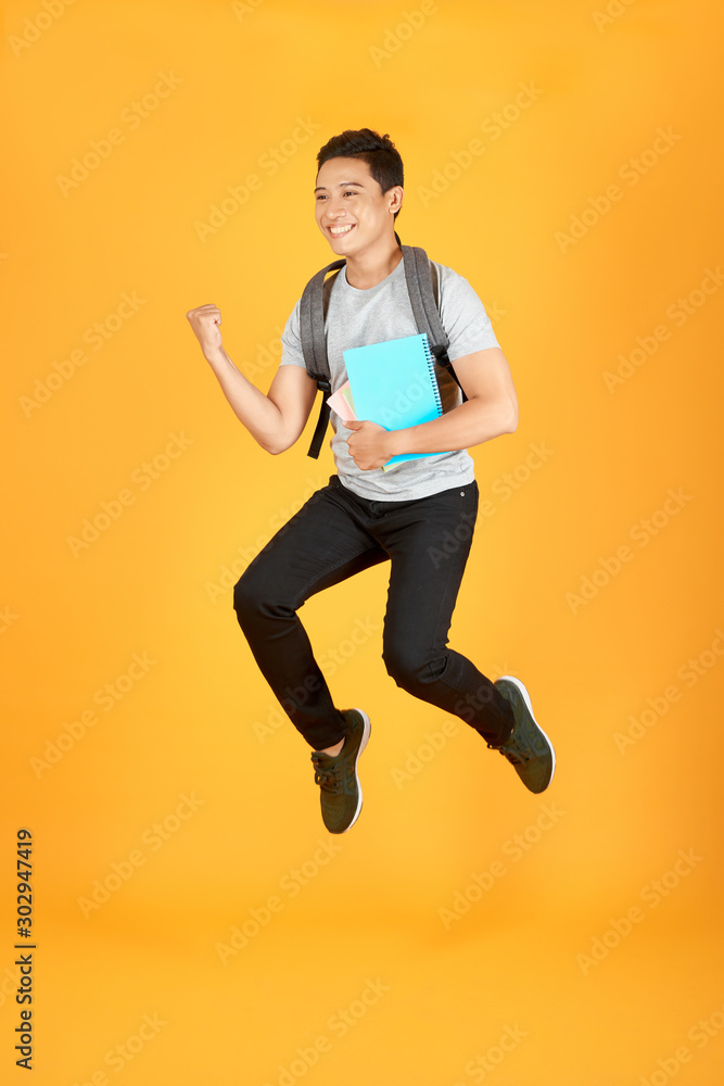 Student man jumping with backpack isolated on orange background