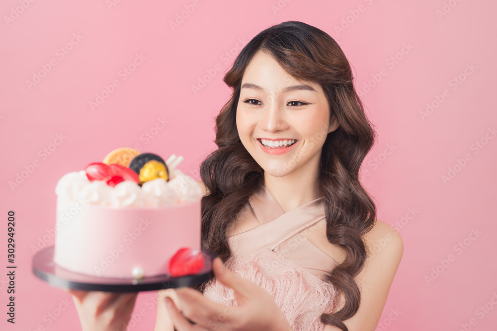 Generous woman holding birthday cake front pink background