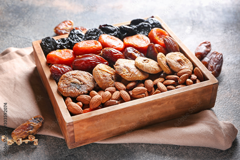 Box with different dried fruits and nuts on grey background