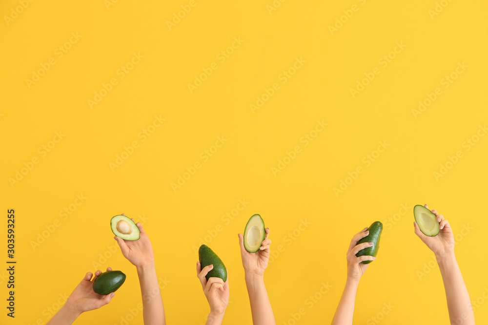 Female hands with fresh avocados on color background