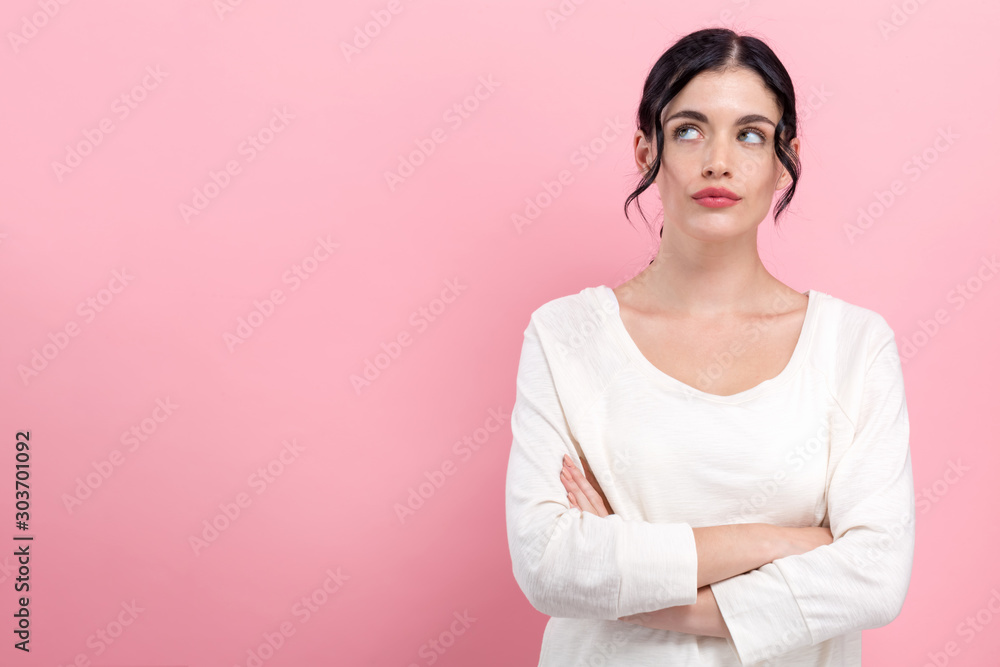 Young woman in a thoughtful pose on a pink background