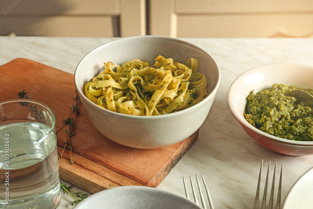 Bowl with tasty pasta and pesto sauce on table