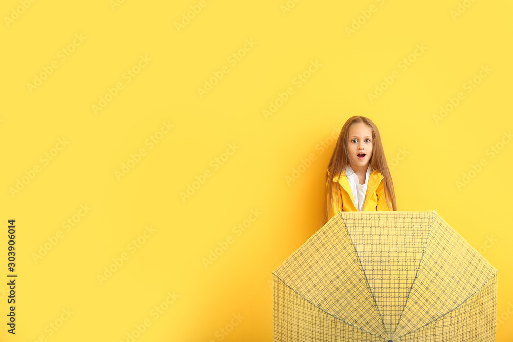 Fashionable little girl in autumn clothes and with umbrella on color background