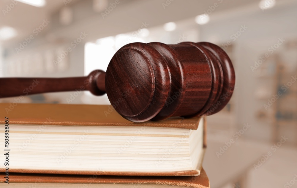 Books and wooden judge gavel on old wooden table.