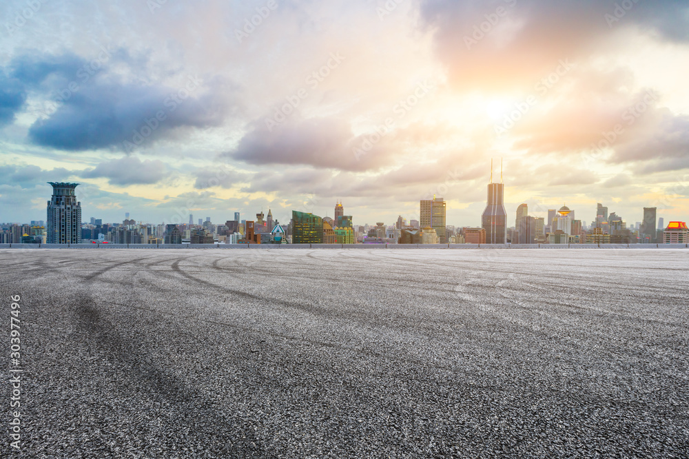 Empty asphalt race track and modern city skyline in Shanghai at sunset.