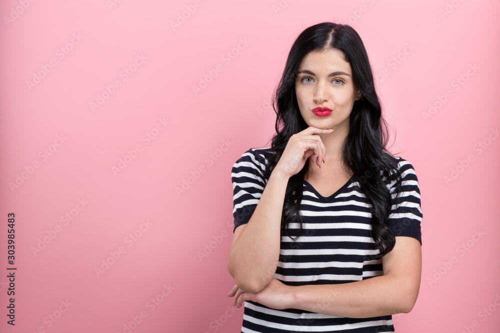 Young woman in a thoughtful pose on a pink background