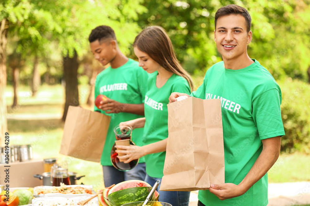 Young volunteers with food for poor people outdoors