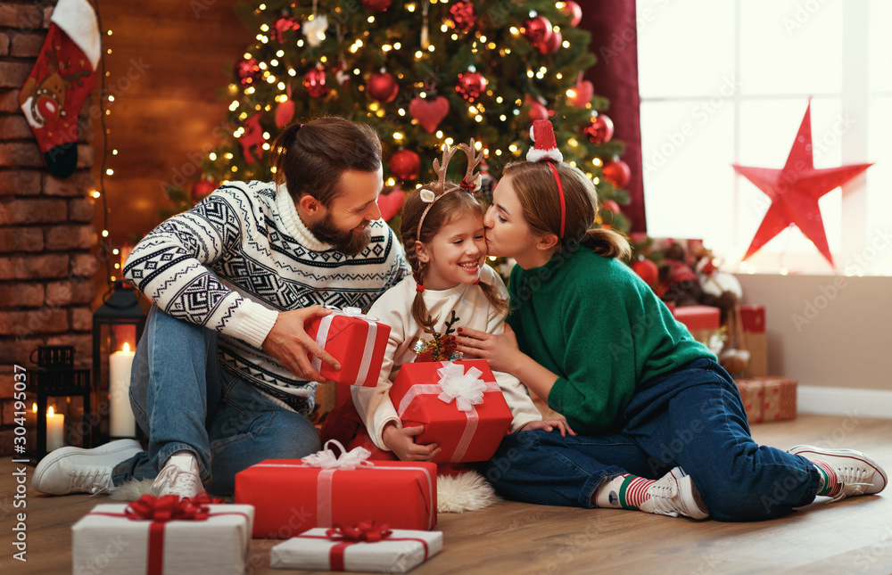 happy family mother, father and child  with gifts near   Christmas tree at home.