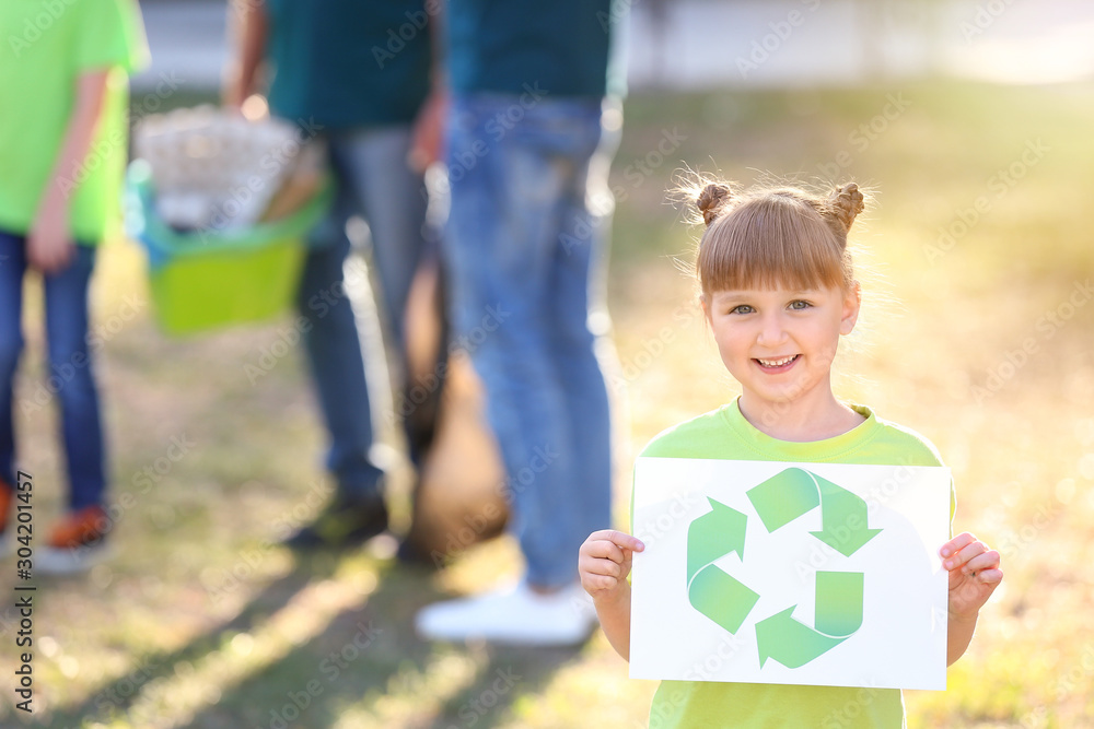 Girl holding paper sheet with symbol of recycling outdoors