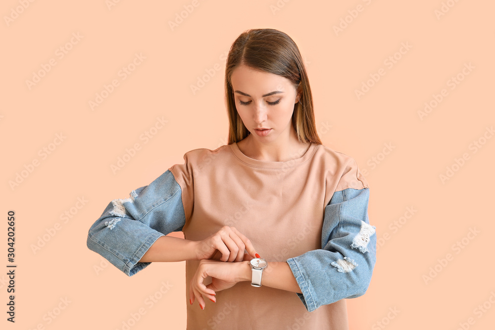 Beautiful young woman with watch on color background