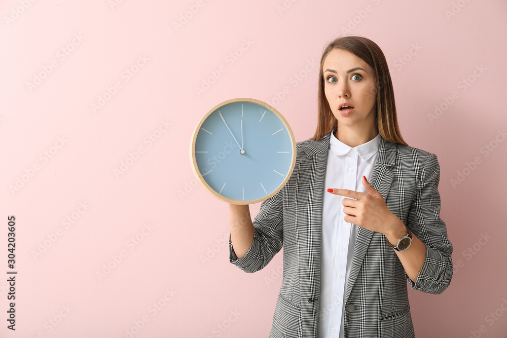 Young businesswoman with clock on color background