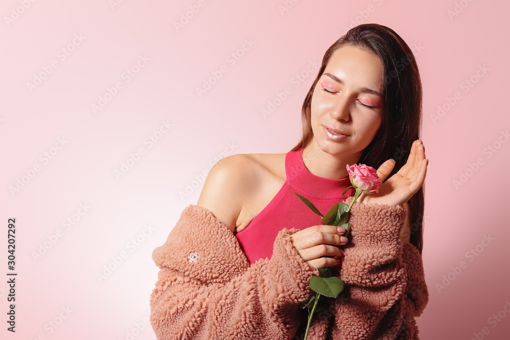 Fashionable young woman with flower on color background