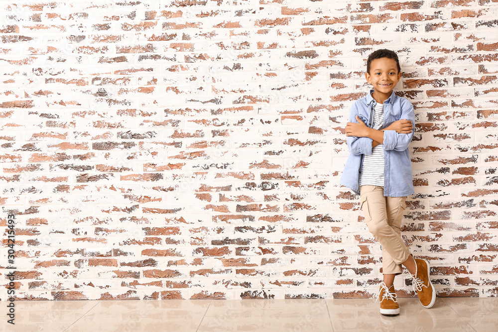 Fashionable African-American boy near brick wall