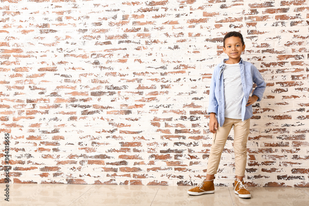 Fashionable African-American boy near brick wall