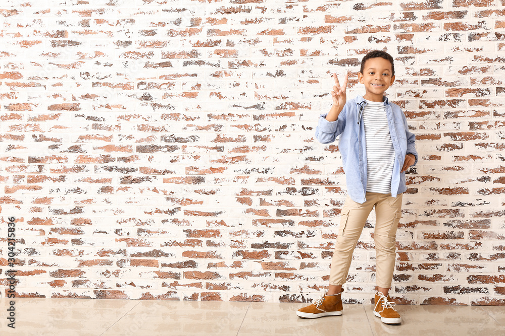 Fashionable African-American boy near brick wall