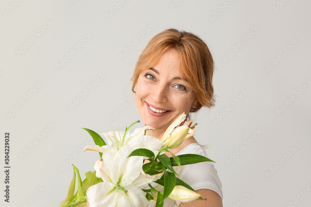 浅色背景上有美丽花朵的成熟女人