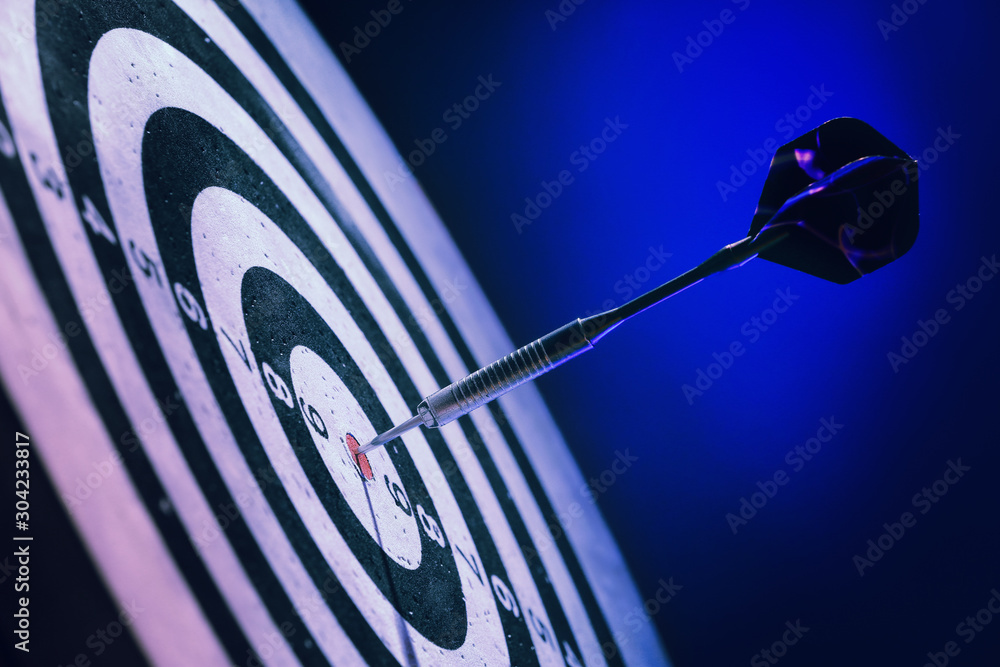 Dartboard with hit bullseye on dark color background, closeup