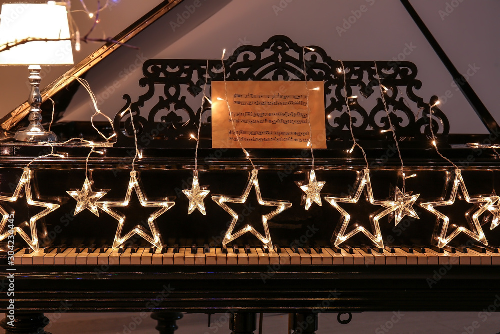 Piano with glowing Christmas garland in room