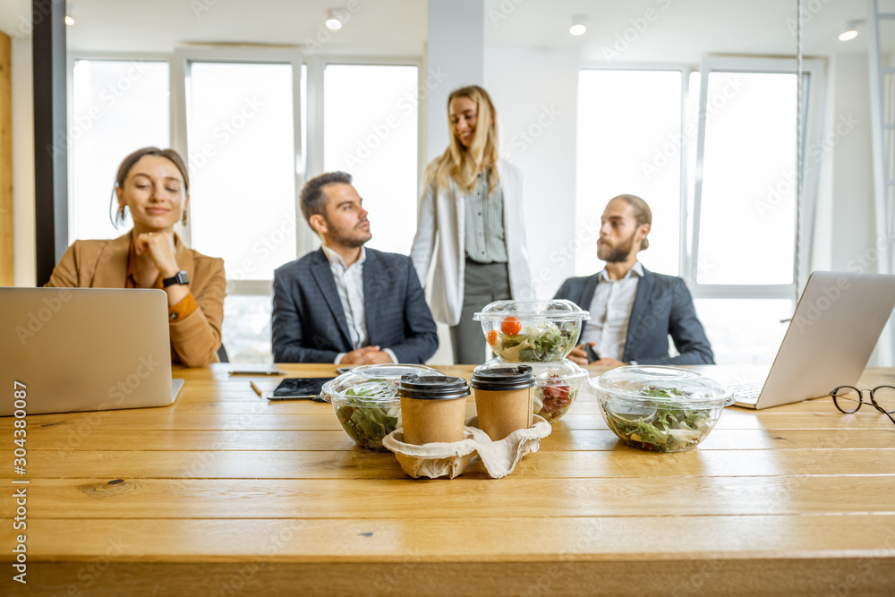 Office workers sitting in the office with business lunches on the foreground. Concept of healthy tak