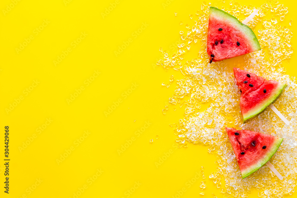 Cut watermelon on stick for break with fruit popsicle on yellow background top view mockup