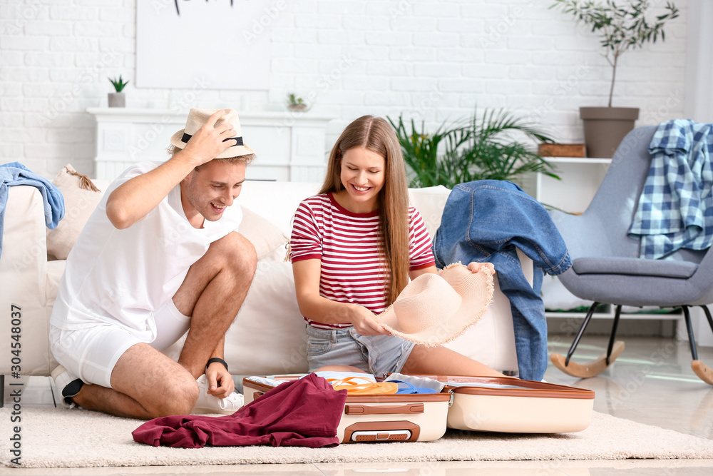 Young couple packing suitcase at home