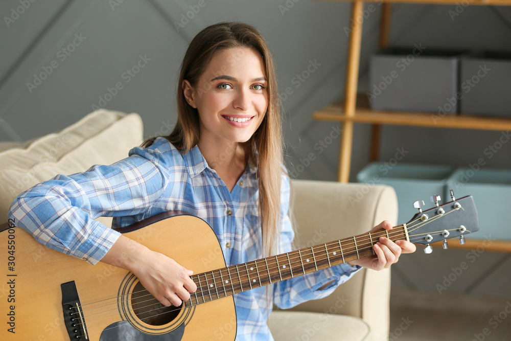 Young woman playing guitar at home