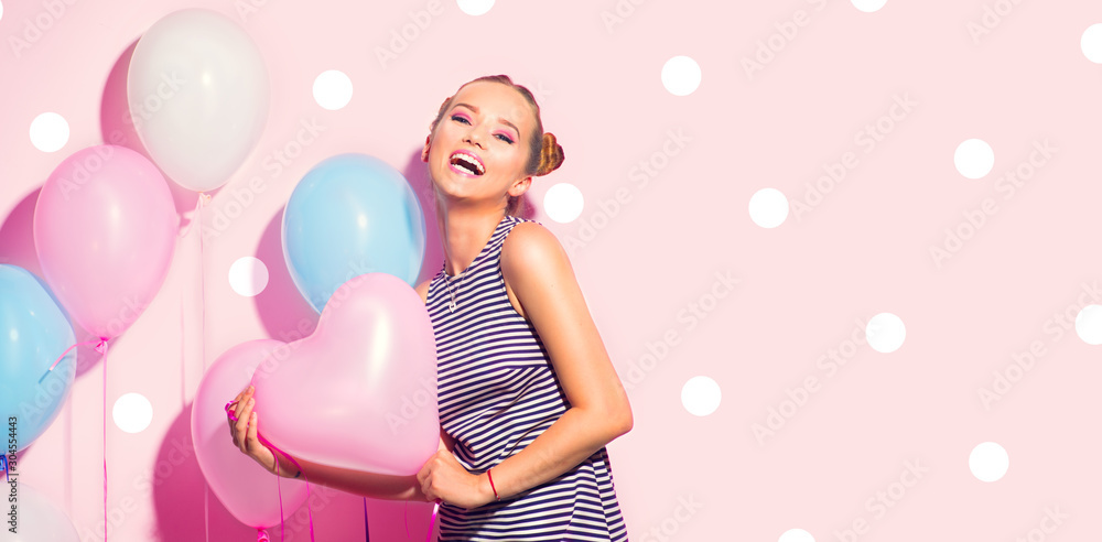 Beauty girl with colorful air balloons laughing over pink background. Beautiful Happy Young woman on