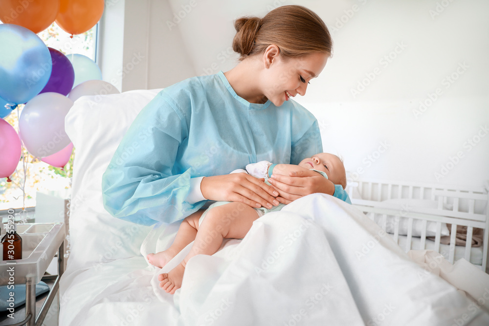 Young mother with newborn baby in maternity hospital