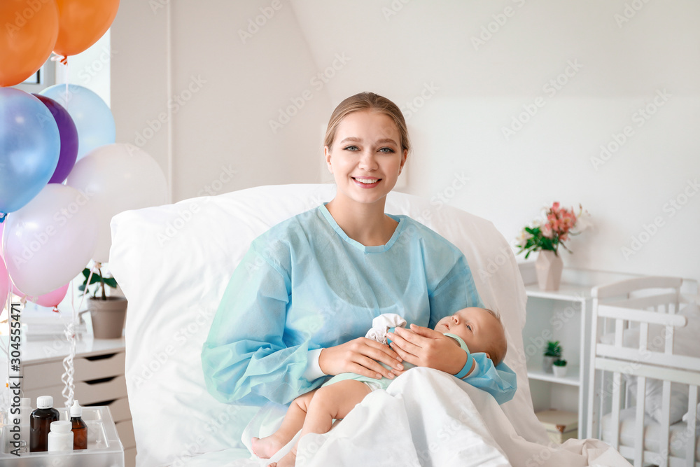 Young mother with newborn baby in maternity hospital