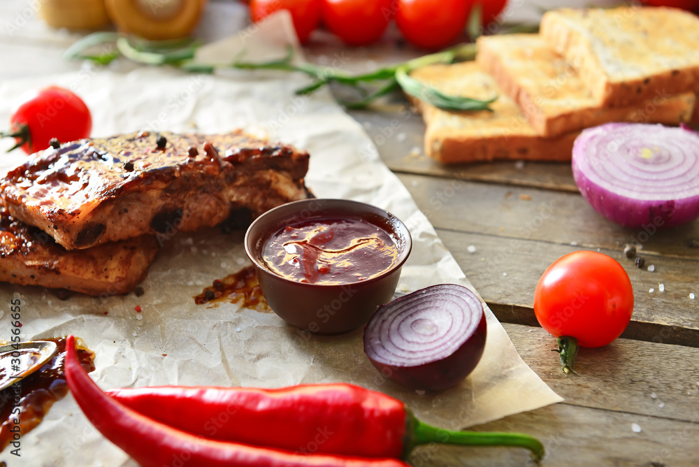 Tasty grilled meat with barbecue sauce, vegetables and spices on table