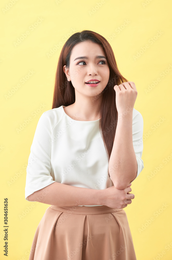 Asian young beautiful woman smiling and touching smooth her hair on yellow background