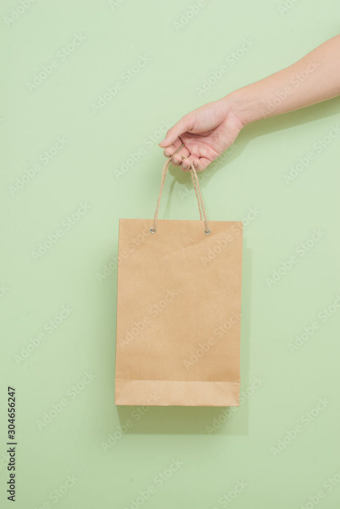 Woman holding paper shopping bag on green background