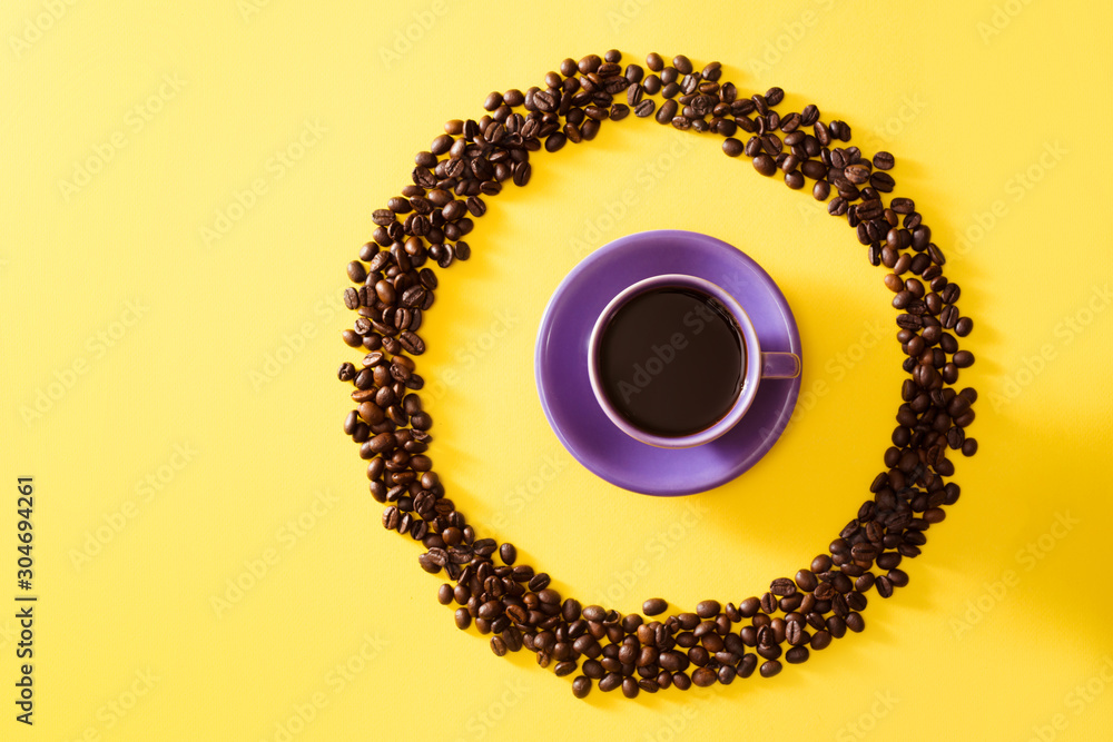 Cup of coffee in circle shape coffee beans on yellow background