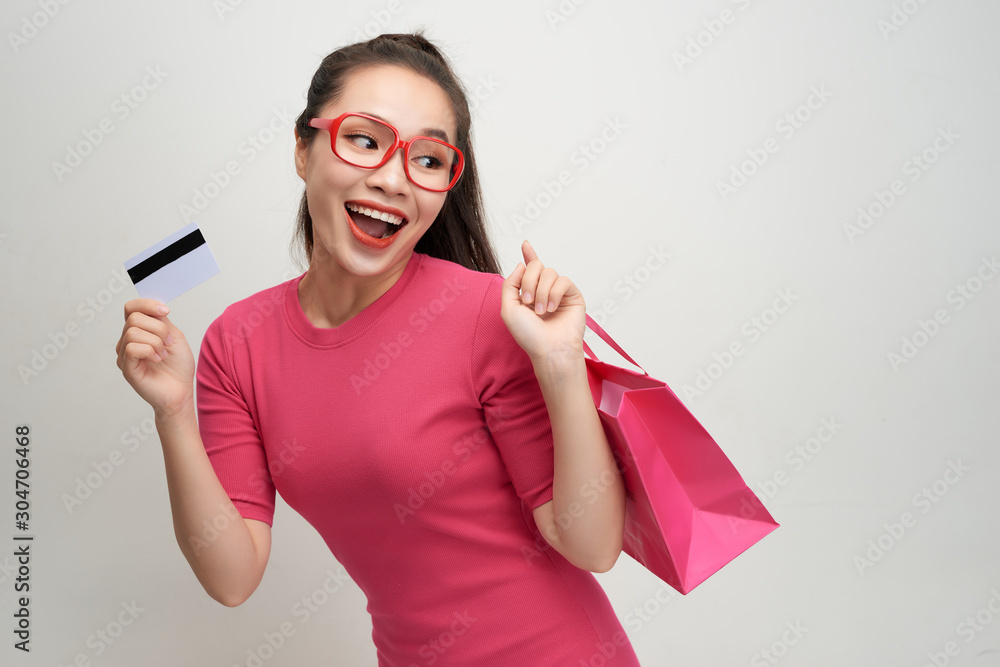 Image of excited screaming young woman standing holding shopping bags and credit card.