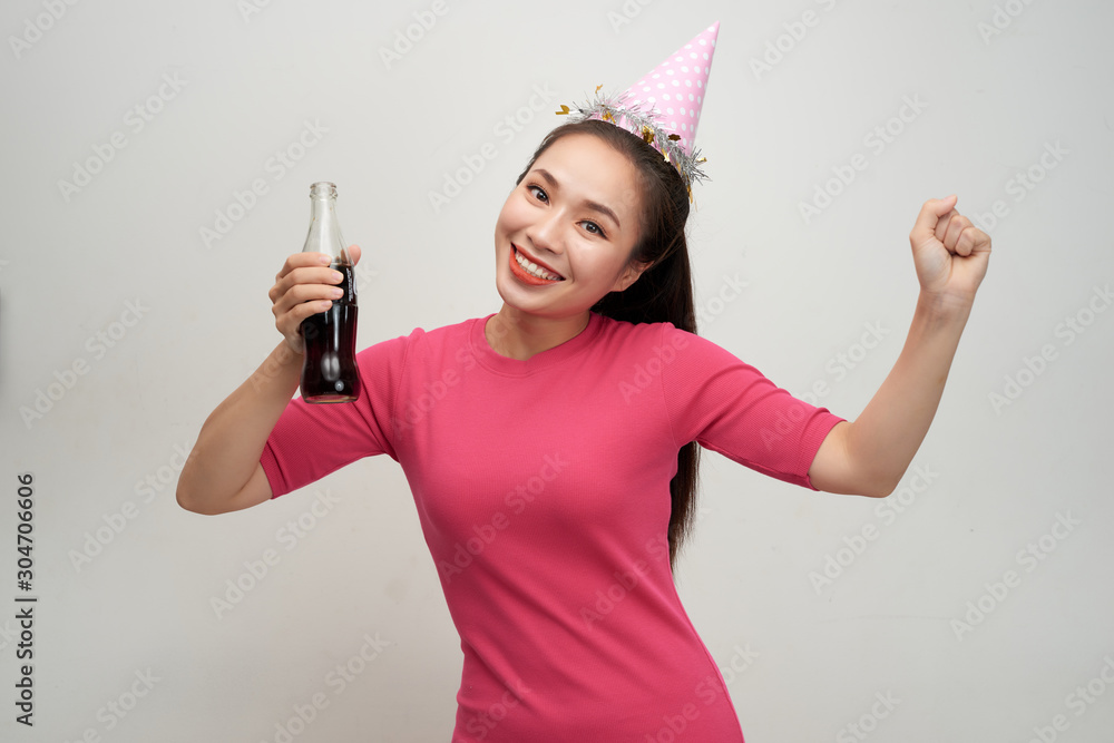 Stylish asian woman drinking soda dancing over white background