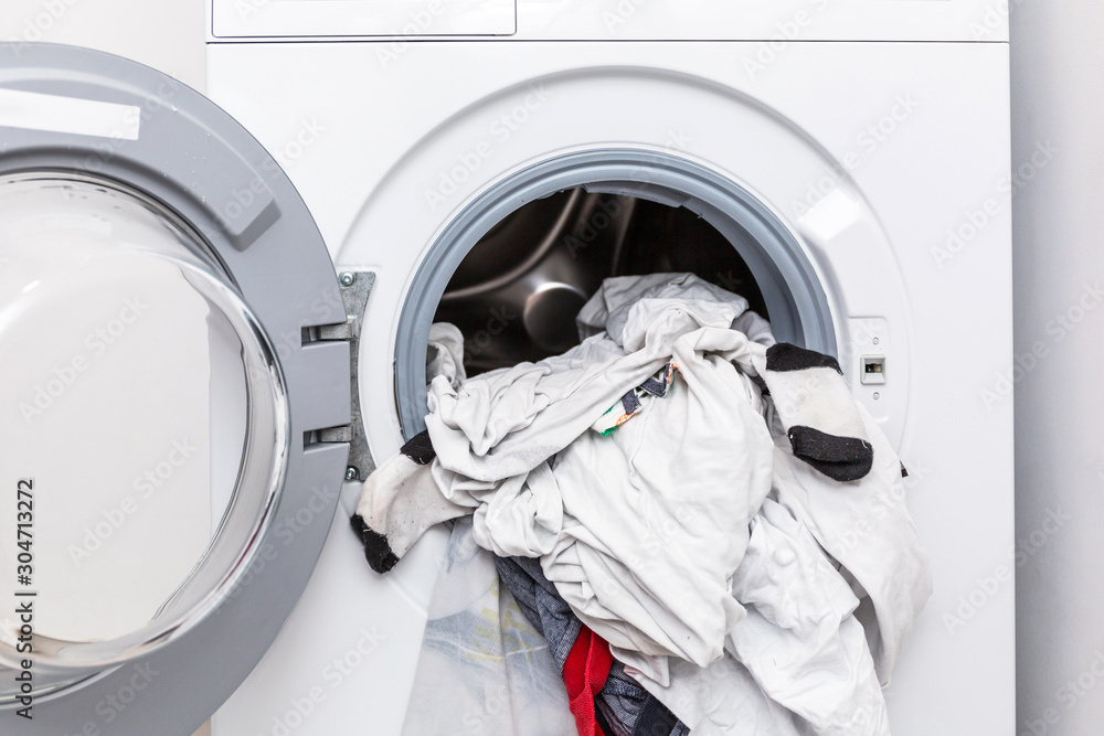 Electric washer with clothes inside in the laundry room