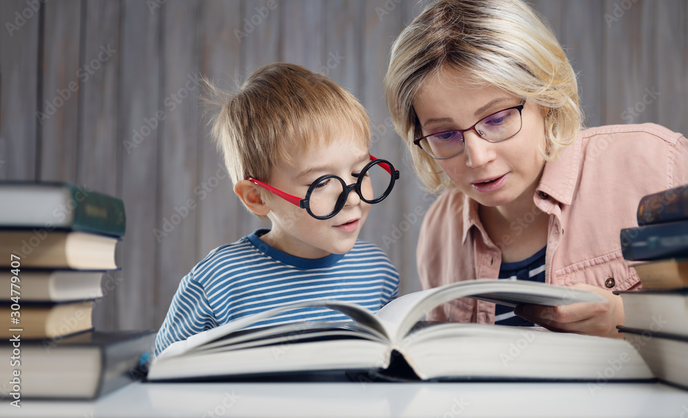 five years old child reading a book at home with mother