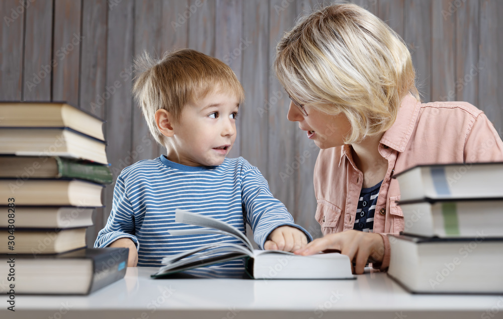 five years old child reading a book at home with mother