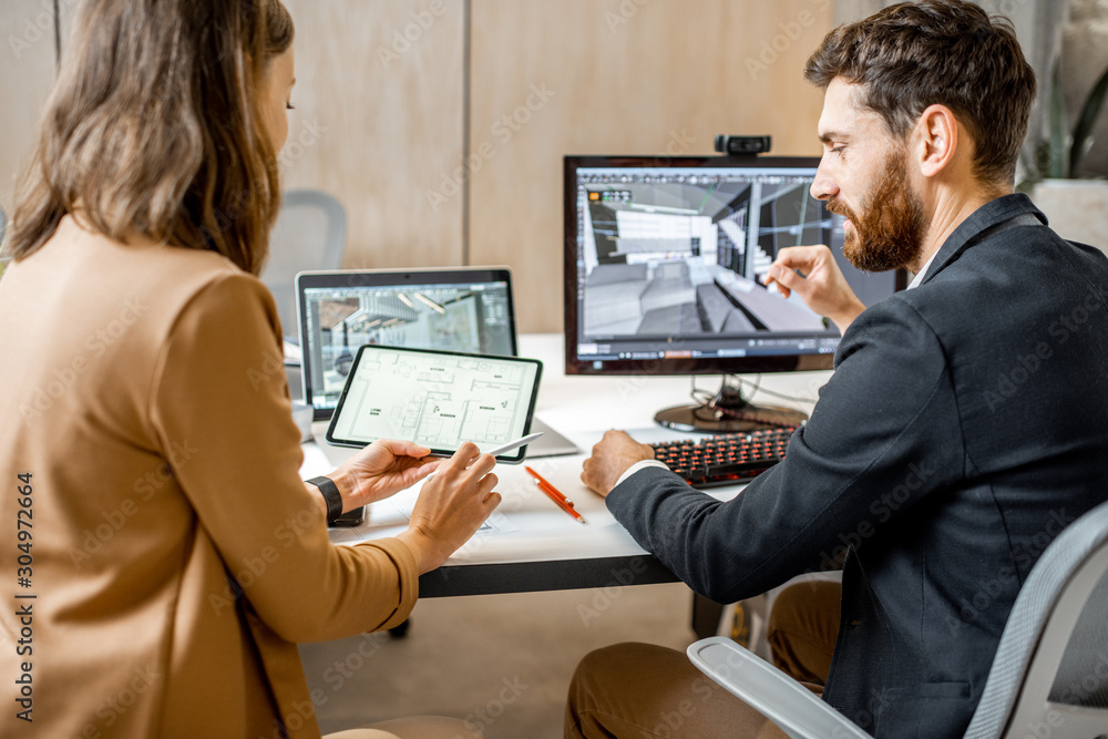 Two creative office employees making interior design on the computer and digital tablet at the moder