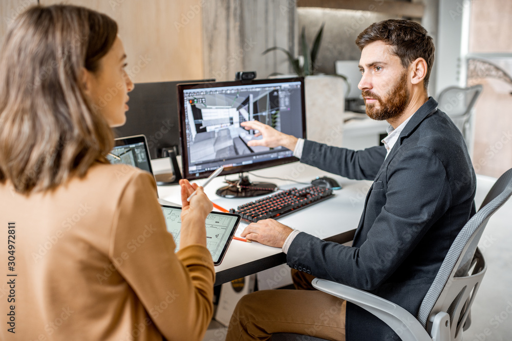 Two creative office employees making interior design on the computer and digital tablet at the moder