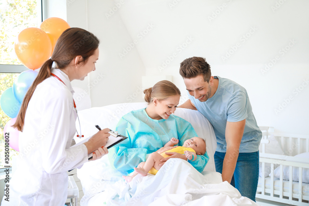 Young family with newborn baby and gynecologist in maternity hospital