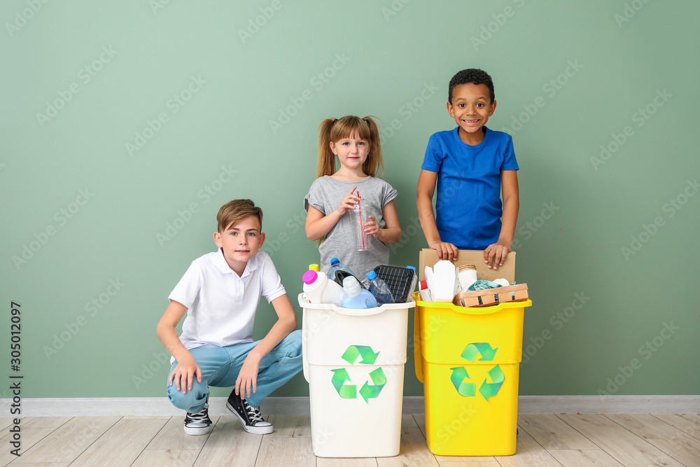 Little children and containers with trash near color wall. Concept of recycling