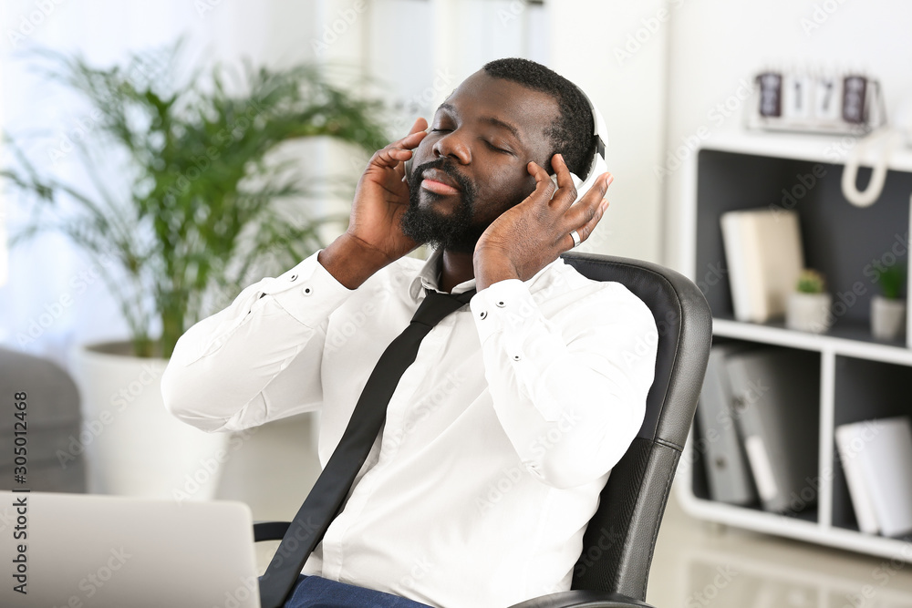 Handsome African-American man listening to music in office