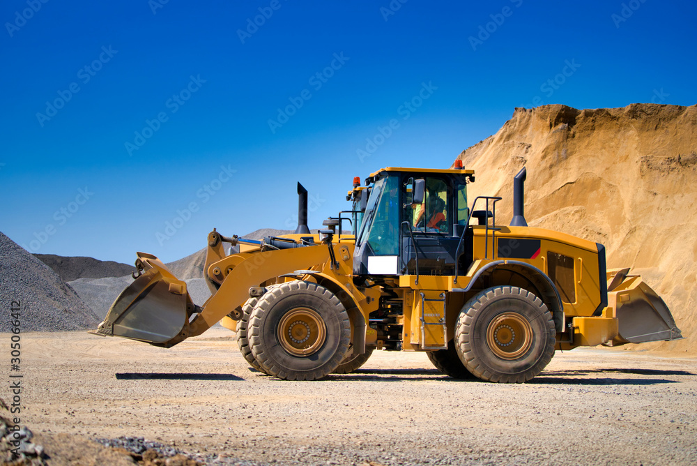 Yellow wheel skid-steer loader machine, loading gravel at construction. Worksite outdoor, heavy equi